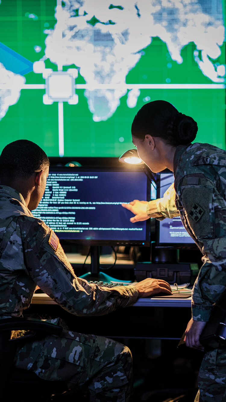 Two Army Cyber Soldiers monitoring computer screens.