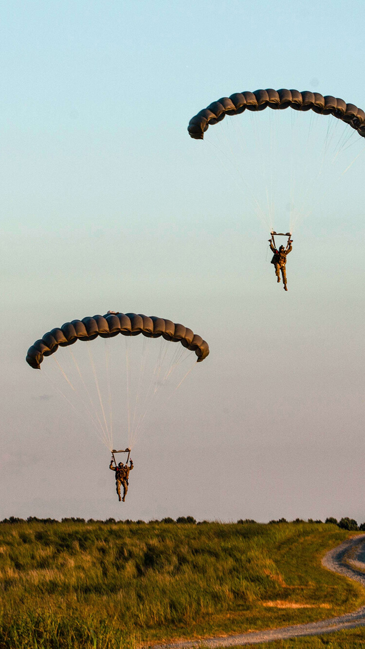 Two Army paratroopers floating from parachutes.